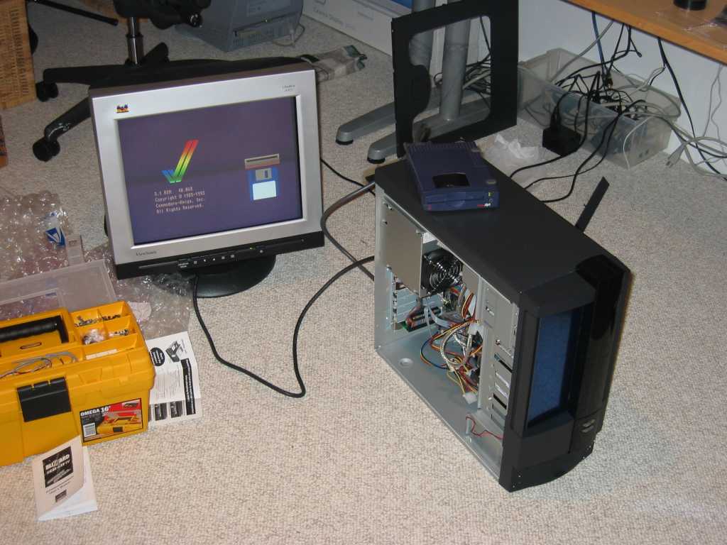 A computer tower opened, exposing the internal componentes of the computer, connected to a monitor on the floor.