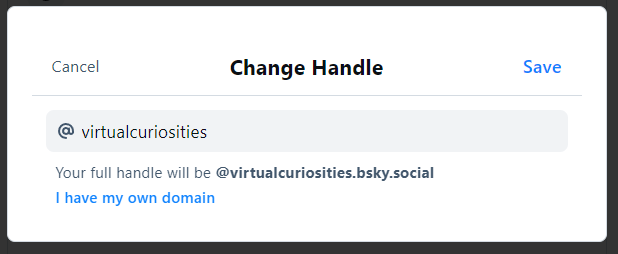 A dialog box with the title "Change Handle." In it a text field with an at (@) symbol as label, its value: "virtualcuriosities." A message: "Your full handle will be @virtualcuriosities.bsky.social." A link at the bottom that says "I have my own domain." Two buttons: Save and Cancel.