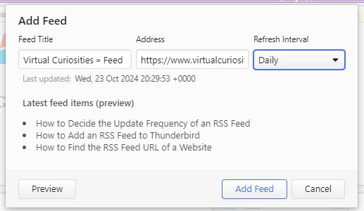 A dialog window titled "Add Feed." It has three fields: Feed Title (value: Virtual Curiosities » Feed), Address (value: https://ww.virtualcuriosi...) Refresh Interval (value: Daily). Under the fields it says: Last updated: Wed, 23 Oct 2024 20:29:53 +0000. Latest feed items (preview) How to Decide the Update Frequency of an RSS Feed; How to Add an RSS Feed to Thunderbird; How to Find the RSS Feed URL of a Website. Three buttons: Preview, Add Feed and Cancel.